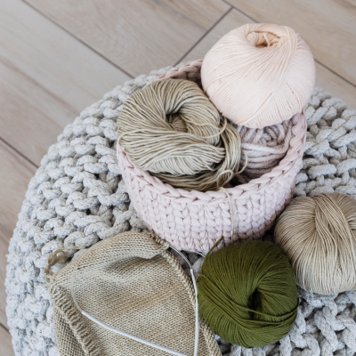 Novelos de lã coloridos com agulhas de tricô sobre manta cinza