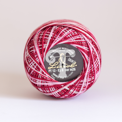 Novelo de fio colorido vermelho, branco e rosa com rótulo preto central