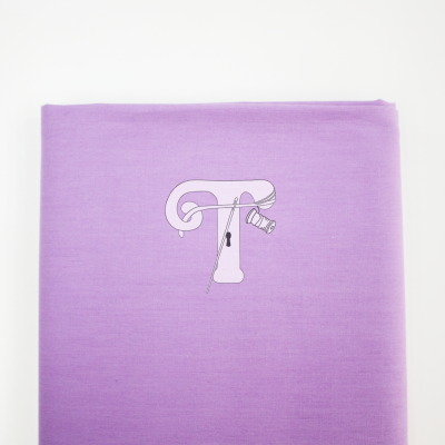 tecido lilás dobrado com grafismo de linha e alfinete