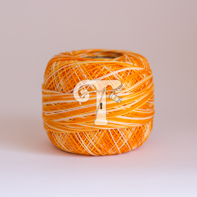 Novelo de linha laranja e branco sobre superfície branca