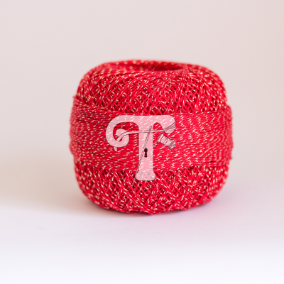 Novelo de fio vermelho com fios metálicos dourados e etiqueta com letra T