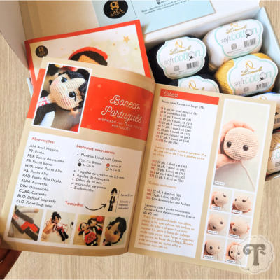 Revista aberta com instruções para boneco de crochê e novelos de linha Lindol Soft Cotton
