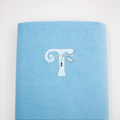 Rolo de tecido azul claro com letra T e agulha desenhados