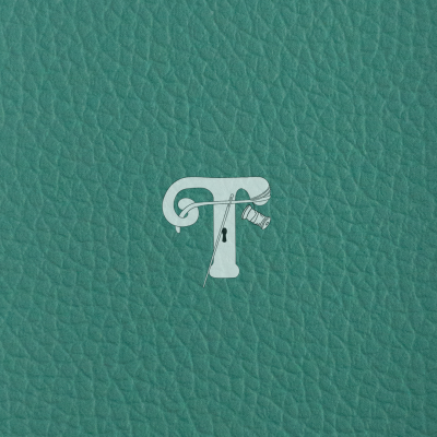 Superfície verde de couro com letra 'T' branca e agulha com linha