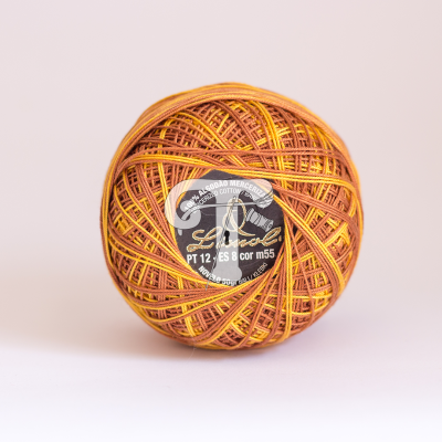 Novelo de linha de algodão Linrol em tons amarelo e castanho com etiqueta preta e branca