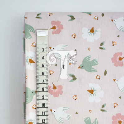 Tecido rosa com pássaros verdes e flores cor-de-rosa, fita métrica ao lado.