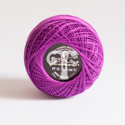 Novelo de linha de algodão mercerizado roxo com etiqueta preta e texto.