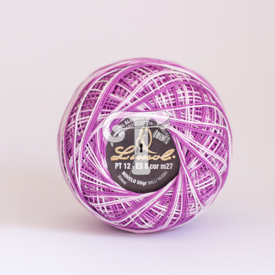 Rolo de fio de algodão em tons de rosa, branco e lilás com etiqueta preta.