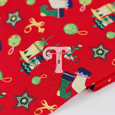 Tecido vermelho com padrões natalícios coloridos de sinos, meias, estrelas e bolas.