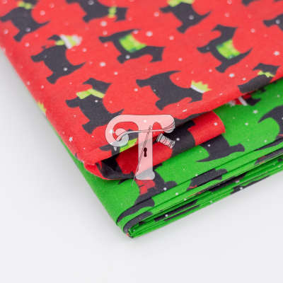 Tecido de algodão com padrão de cães pretos e cachecóis em fundo vermelho e verde