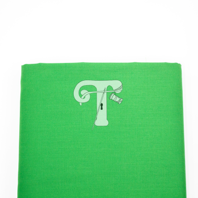 tecido verde com padrão decorativo e agulha