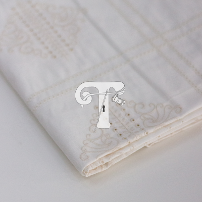 Toalha branca bordada com padrão bege dobrada