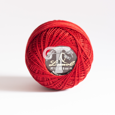 Novelo de linha vermelha com etiqueta preta e texto branco