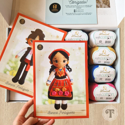 Caixa com novelos de lã coloridos e cartas com imagens de bonecas portuguesas em trajes tradicionais