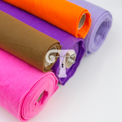 Rolos de tecido de feltro colorido laranja, roxo, castanho e rosa sobre fundo branco