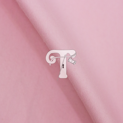 tecido cor-de-rosa claro com letra T ilustrada com agulha e linha