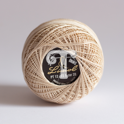 Novelo de linha fina bege claro com etiqueta preta e texto preto e amarelo