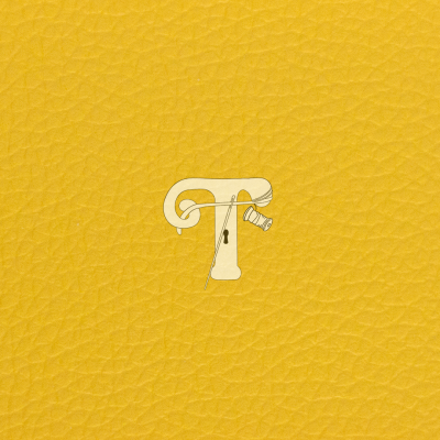 Tecido amarelo de couro com letra T branca decorada com agulha e linha