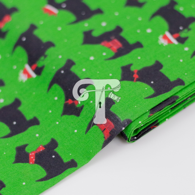 tecido verde com padrão de cães pretos e laços vermelhos