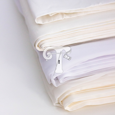 Três peças de tecido dobradas em tons creme e branco