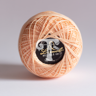 Rolo de linha bege claro com etiqueta preta e dourada no centro sobre fundo branco