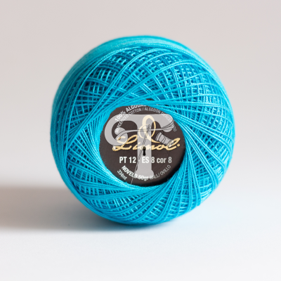 Novelo de linha azul turquesa com etiqueta preta ao centro