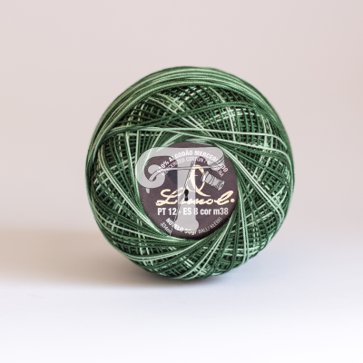 Rolo de linha verde com etiqueta preta e branca num fundo branco