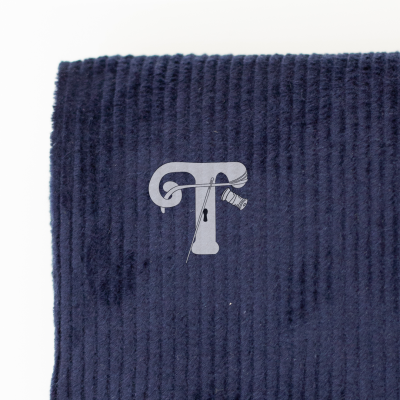 Pano azul escuro com bordado branco da letra T estilizada