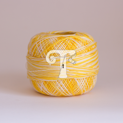 Rolo de fio torcido branco e amarelo sobre superfície branca com fundo bege