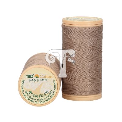 Dois carretéis de linha de algodão bege claro da marca mez, um em pé e outro deitado com etiqueta visível