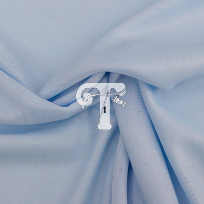 tecido azul claro com textura lisa em pregas suaves e logotipo central com agulha, linha e fita métrica