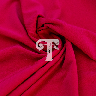 Tecido vermelho com padrão enrolado e gráfico de 'T' com agulha e linha