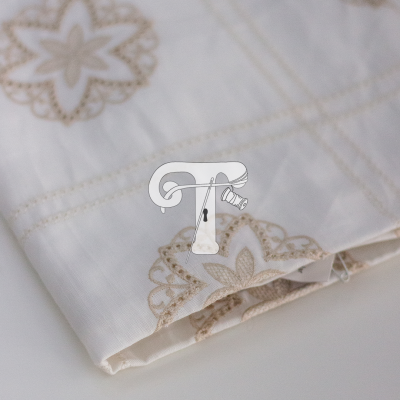 Tecido branco com padrão floral bege e bordado delicado dobrado