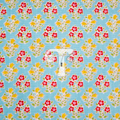 Tecido estampado com padrão floral em amarelo, vermelho e verde sobre fundo azul claro