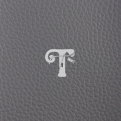 Superfície cinza com textura de pele e um logótipo branco com a letra T e detalhes