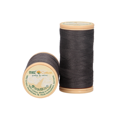 Dois carretéis de fio de algodão castanho escuro com etiquetas redondas na parte superior.