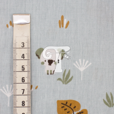 Tecido azul claro com padrão de ovelhas e folhas acompanhado de fita métrica.