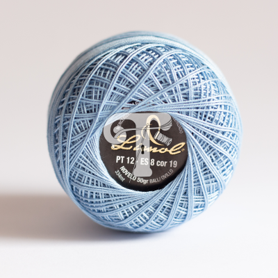 Novelo de linha azul claro com etiqueta preta e dourada