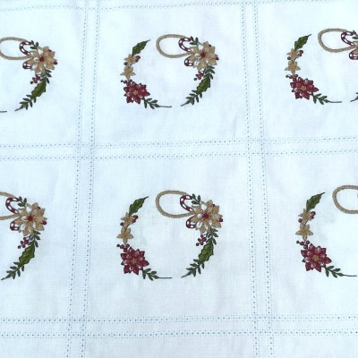 Tecido branco bordado com flores coloridas formando guirlandas decorativas