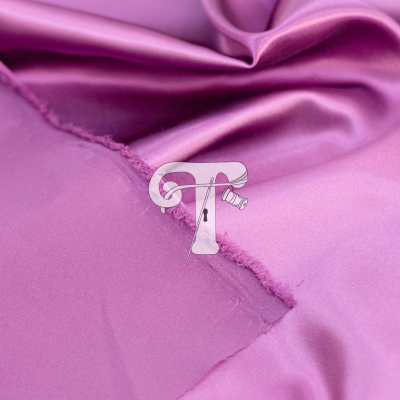 Detalhe de tecido de cetim lilás com agulha e linha branca na costura