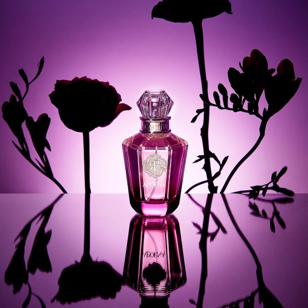 Frasco de perfume rosa com tampa transparente e flores em silhueta sobre fundo rosa