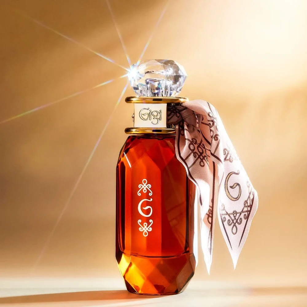 Frasco de perfume âmbar com tampa facetada transparente e lenço rosa com padrão