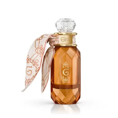 Frasco de perfume âmbar com tampa transparente e lenço branco com padrão laranja.