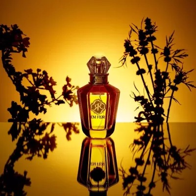 Frasco de perfume âmbar com tampa transparente e rótulo EM FLOR em fundo amarelo com flores pretas