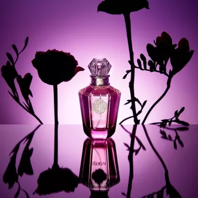 Frasco de perfume rosa com tampa transparente e flores em silhueta sobre fundo rosa