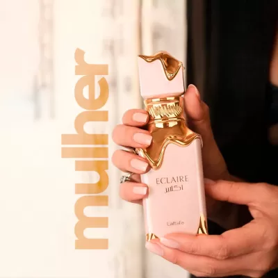 Frasco de perfume cor de rosa com detalhes dourados segurado por duas mãos femininas