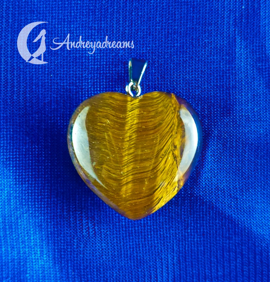 Pendente 💛 Coração Olho de Tigre Pingente coração âmbar com base prata sobre tecido azul com texto Andreyadreams