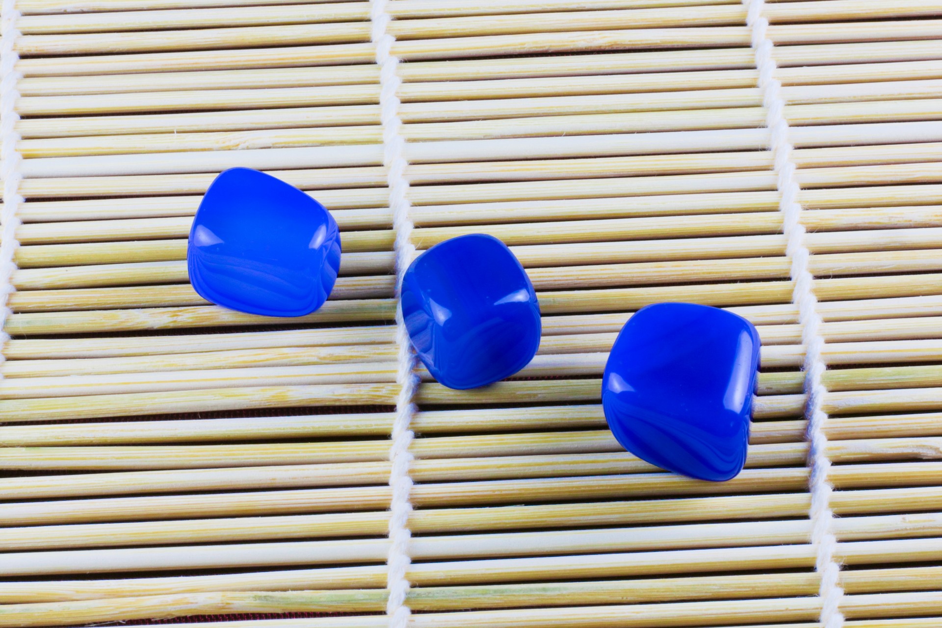 Ágata Azul Três contas azuis brilhantes sobre tapete de bamboo claro