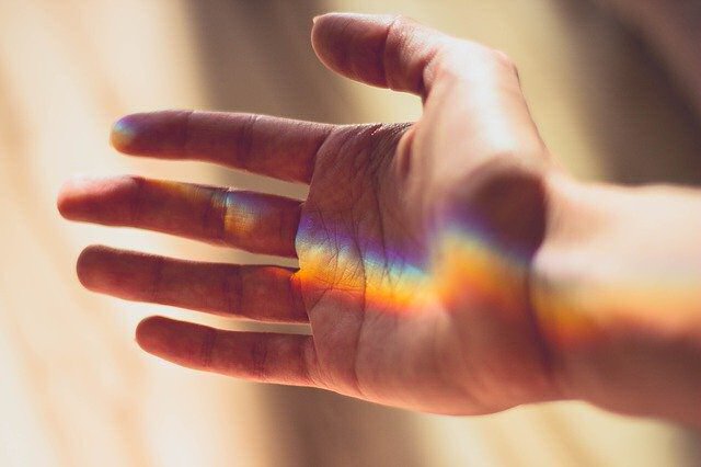 Reiki à Distância Mão aberta com faixa de luz colorida tipo arco-íris na pele