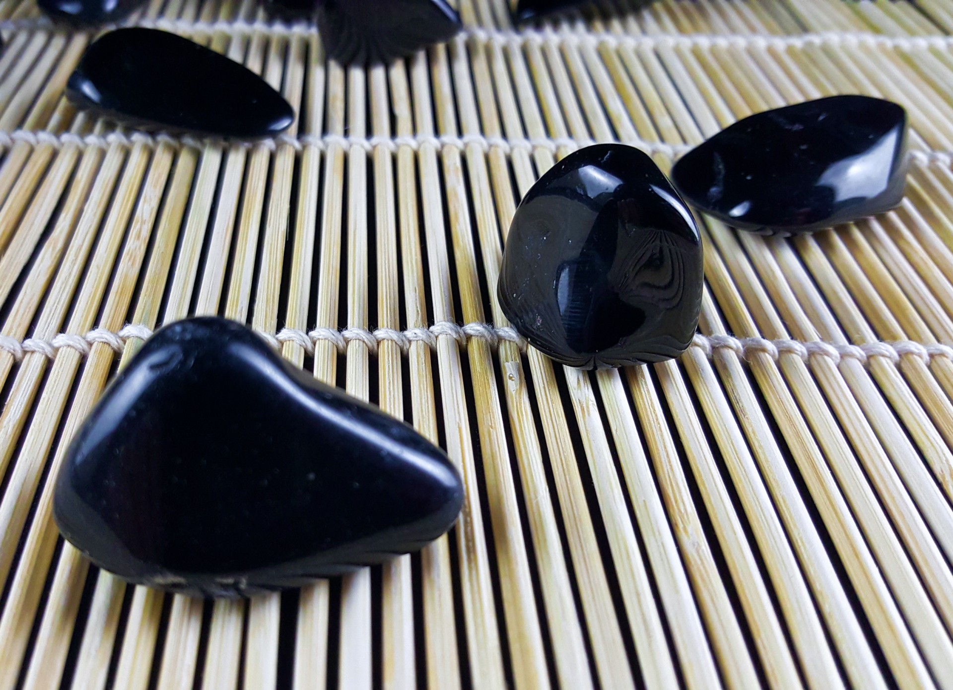 Turmalina Preta Rolada Pedras polidas pretas sobre esteira de bambu clara